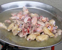 Frying the chicken and pork to make Paella